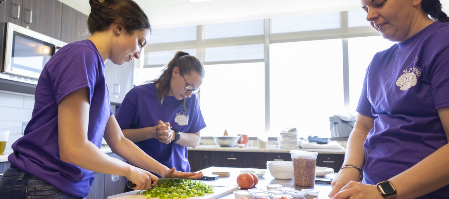 Students in kitchen lab chopping vegetables
